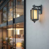 Outdoor lantern wall light in sandy black finish with warm amber glass shade