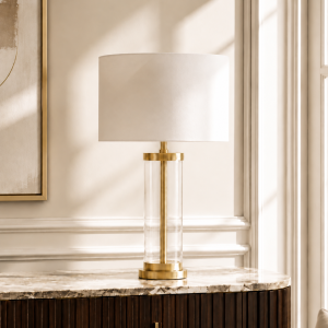 LLT Empire White Gold Table Lamp with clear glass cylinder base, brass finish metal detail and off-white drum shade against white background